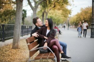 couple on a bench smiling at one another.
